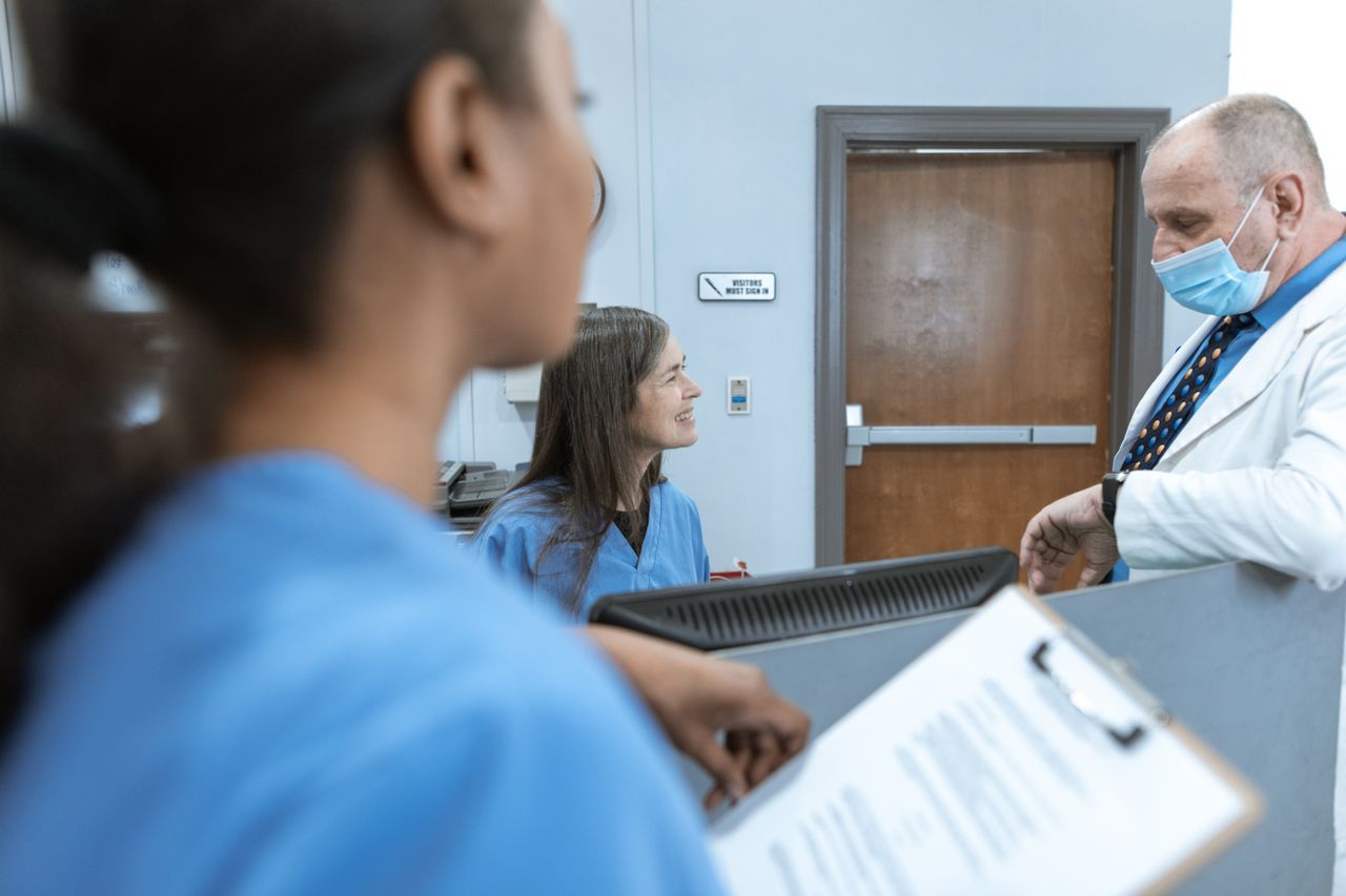 The Art of Drawing Readers In: Your attractive post title goes here Healthcare professionals in discussion at a hospital reception, emphasizing teamwork and communication.